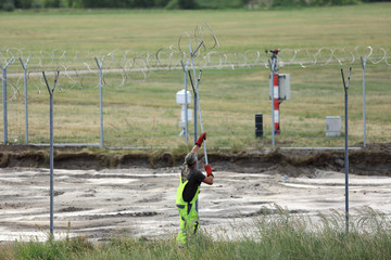Budowa ogrodzenia, zakładanie drutu kolczastego wokół lotniska w Pyrzowicach. - obrazy, fototapety, plakaty