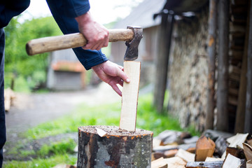 Man hands cutting some piece of wood by axe