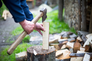 Man hands cutting some piece of wood by axe