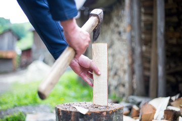 Man hands cutting some piece of wood by axe