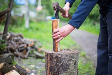 Man hands cutting some piece of wood by axe