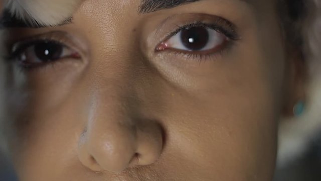 Close-up of Transgender woman applying make-up with brush, looking at the camera