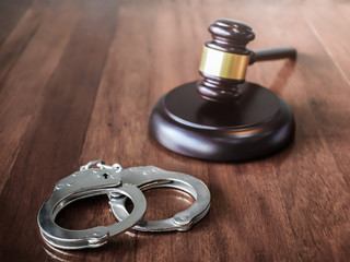 handcuffs and judge gavel on brown wooden table