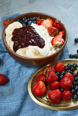 bowl of cottage cheese with berries, bananas and sour cream. fresh berries on wintage copper plate