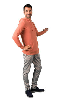 Full body of  Man in a pink sweatshirt pointing back with the index finger presenting a product on isolated white background