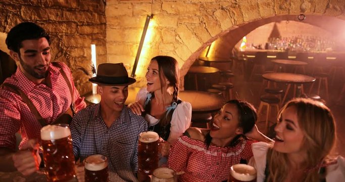 Young multi-ethnic friends celebrating Oktoberfest at Bavarian bar party