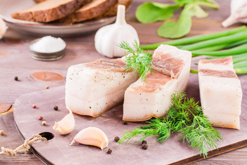 Salted lard with garlic and dill on a cutting board on a wooden table