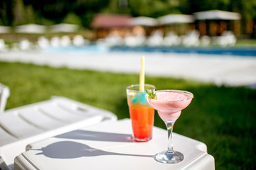 Two luxury summer cocktails on the table near the swimming pool outdoors