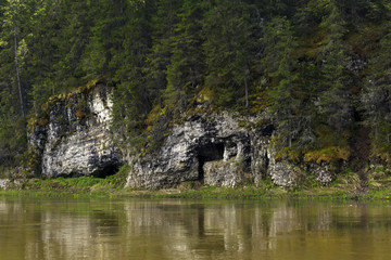 Fototapeta na wymiar natural cave in the limestone cliff of the river bank