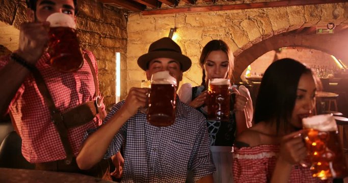 Young multi-ethnic friends with beer mugs and costumes celebrating Oktoberfest