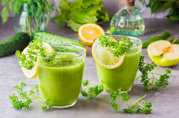 Refreshing smoothies from cucumber, green apple, fresh herbs and lemon juice in transparent glasses...