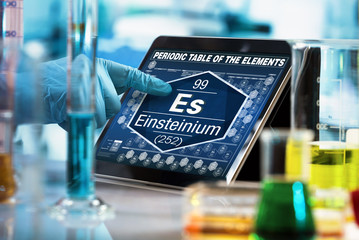 Scientist working on the digital tablet data of the chemical element Einsteinium Es / researcher consulting information on the computer of the periodic table of elements 