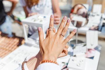 A woman trying on her new ring at outdoor flea handmade market, jewelry and shopping concept