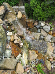 A man made waterfall and stream leading to a Koi fish pond at the bottom 