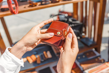 Beautiful young woman choosing leather wallet or purse in the flea market