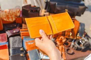 Beautiful young woman choosing leather wallet or purse in the flea market