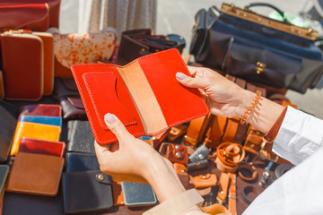 Beautiful young woman choosing leather wallet or purse in the flea market