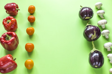 Vegetables spread out on a green background. Red pepper, yellow tomatoes, eggplant, mushrooms