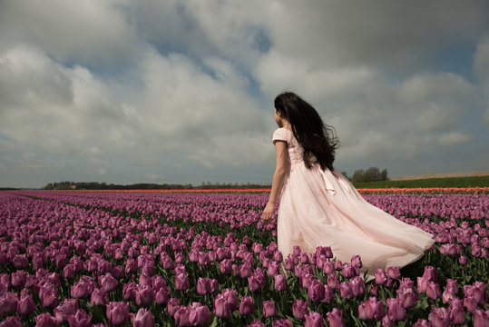 Girl standing in windy tulip field