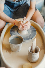 Top view of hands with clay making of a ceramic pot on the pottery wheel, hobby and leisure with pleasure concept