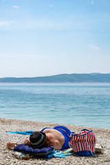 Frau liegt mit Sonnenbrand am Strand