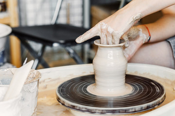 Top view of hands with clay making of a ceramic pot on the pottery wheel, hobby and leisure with pleasure concept