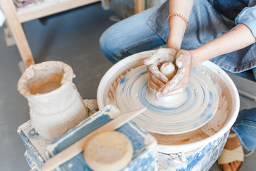 Top view of hands with clay making of a ceramic pot on the pottery wheel, hobby and leisure with pleasure concept