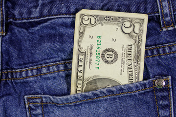Five dollars banknote in the pocket of blue jeans