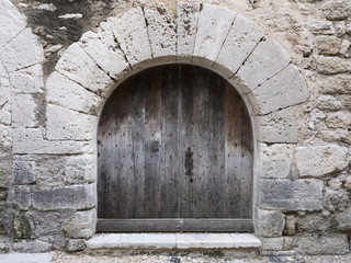 very old grungy dark brown door in limestone wall in french provence