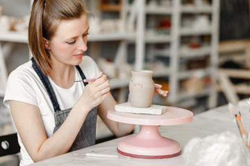 Workshop of clay pottery ceramic, woman decorating dishware pot