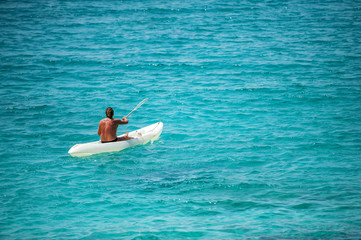 Fototapeta na wymiar A man on a vacation day relaxed with the kayak in a bay on the turquoise and crystalline Mediterranean sea in Sardinia.