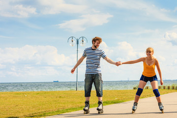 Fototapeta na wymiar Young couple on roller skates riding outdoors