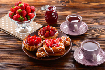 Tea drinking with tartlets and cakes with strawberries