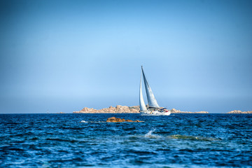 On a sunny summer day a white sailboat whit spinnaker open  sail on  Mediterranean Sea in Sardinia, luxury vacations