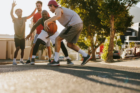 Men playing basketball on street