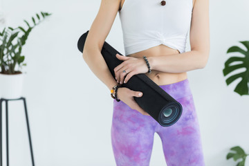 Close-up on hands yoga woman holding her blue mat after a yoga class on white floor, copy space