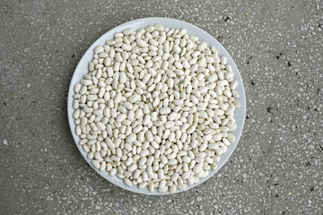 white beans on a plate on granite background