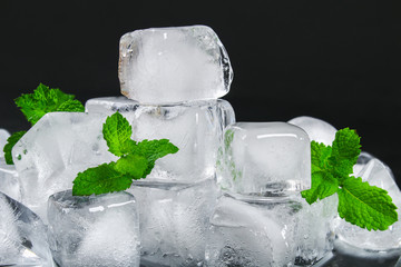 Cubes of ice from water with mint leaves on a black background.