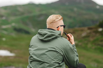 Mann wandert durch die Berge, sitzt und raucht Pfeife