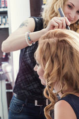 A hairdresser making a haircut for a blonde female client