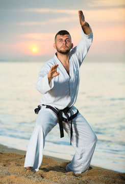 Smiling male doing karate at ocean quay
