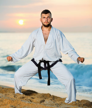 Guy doing karate poses at  sunset sea shore