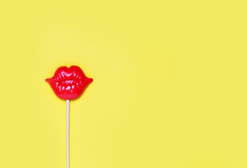 Red plastic lips for fun on yellow festive background.