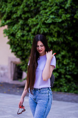 European young beautiful sexy stylish with long hair the girl wears jeans and glasses in a T-shirt,...