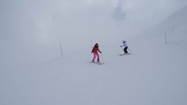 Two Women Skiers Synchronously Turn Carving Skiing On The Mountainside In Winter