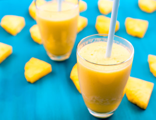 Pineapple smoothie with fresh pineapple on wooden blue table.