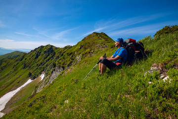Fototapeta na wymiar Tired adventurer is relaxing on the green mountain ridge