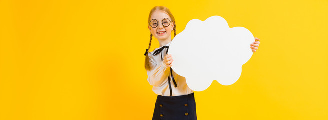 Girl with red pigtails on a yellow background. A charming girl in round transparent glasses is holding a white cloud in her hands.