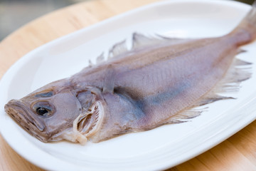 flounder fish on a white plate on wooden table