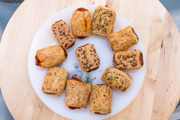 italian pastries with sesame seeds stuffed with sobrasada and cheese on a white plate on wooden table